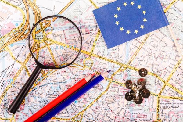 Cartina con lente di ingrandimento, matite, bandiera unione europea e puntine   